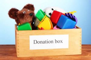 Donation box with children toys on blue background close-up