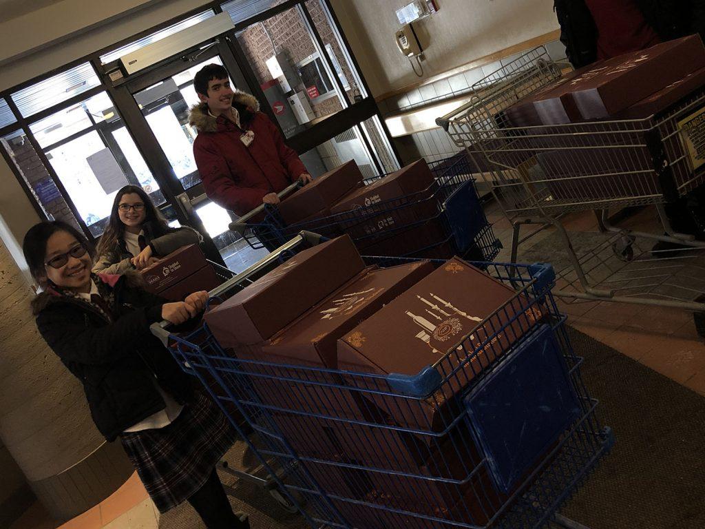 Entering an apartment building with carts full of 'Shabbat to Share' meal boxes