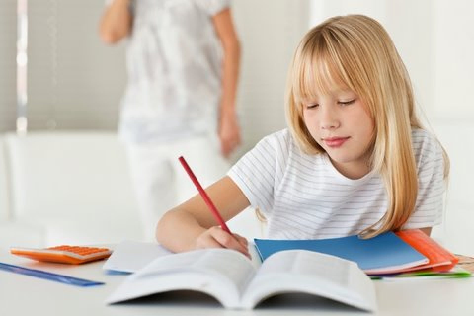 Girl doing homework, Mom in background